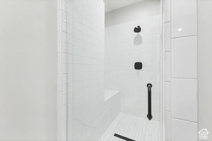 Walk-in shower with white subway tile walls, a built-in bench, and black fixtures