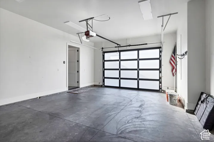 Concrete flooring with a modern garage door featuring frosted glass panels and black framing