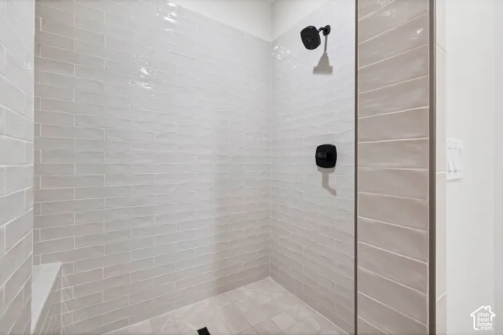 Shower enclosure featuring light grey subway tile, tiled floor, built-in bench, and matte black fixtures