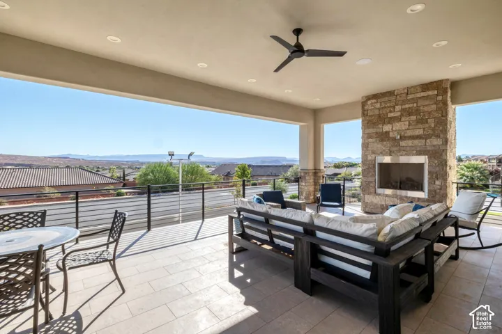 Covered outdoor patio featuring a stone-clad fireplace with a stainless steel insert, recessed lighting, and a ceiling fan