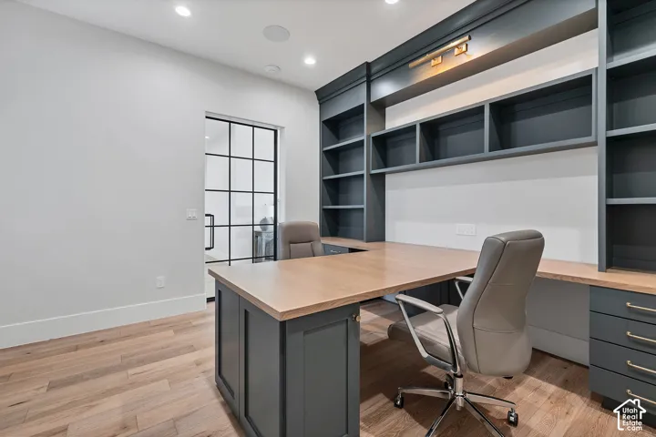 Built-in desk with wood-finish countertop, integrated shelving, recessed lighting, and wood-finish flooring
