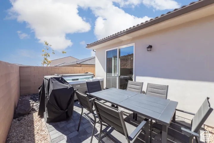 Private patio area featuring a built-in spa, sliding glass door, exterior wall lantern, and concrete block fencing
