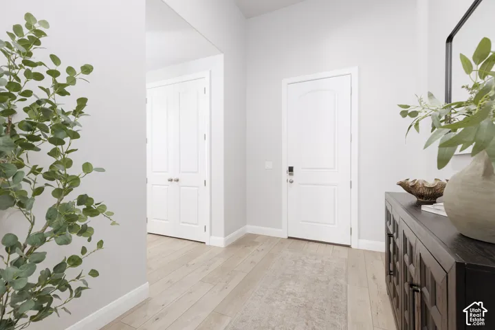 Light wood-finish flooring, white paneled doors, and light gray wall finishes create a bright interior