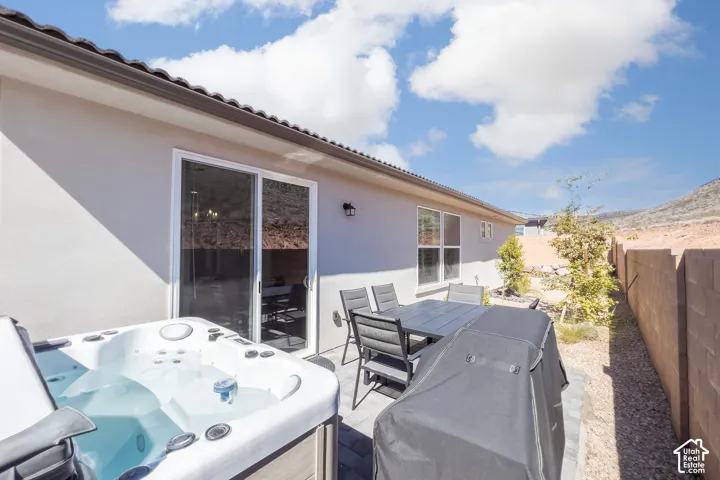 Outdoor living space featuring a built-in hot tub, paver patio, and sliding glass door access