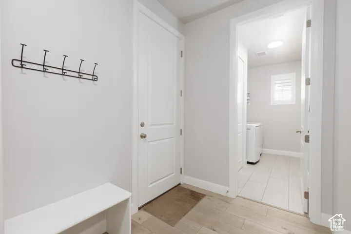 Laundry area with light wood-finish flooring, white paneled doors, and a skylight