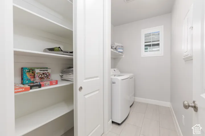 Laundry area with tile flooring, built-in shelving, and a window