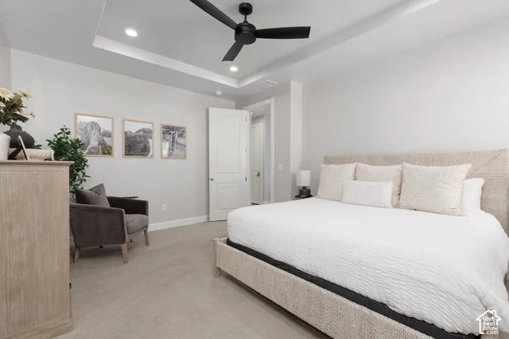 Tray ceiling with recessed lighting and a ceiling fan, light gray wall paint, and light-colored carpeting
