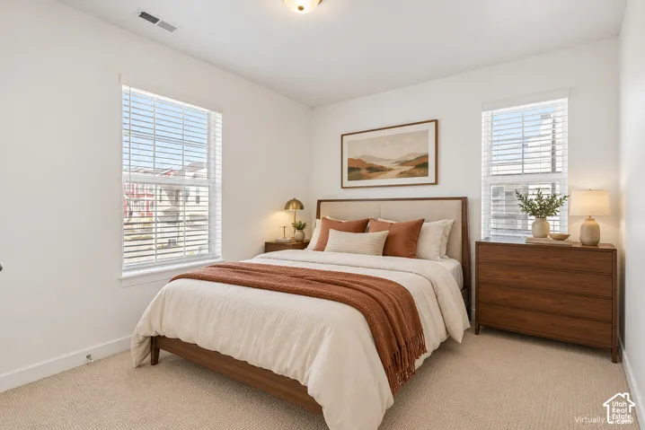 Plush carpeting and bright white walls with two windows featuring blinds