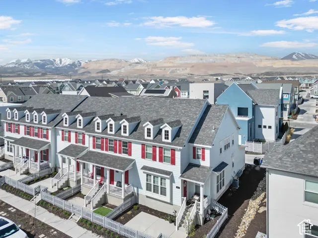 Row of townhomes featuring white siding with red shutters, grey shingled roofs, and white picket fences
