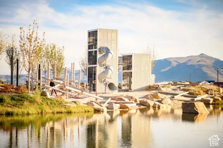 Waterfront community playground featuring multiple slides, climbing structures, and a sandy play area