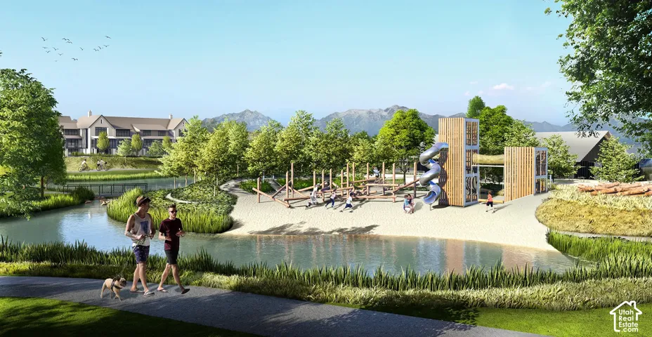 Community green space featuring a water element, sand-lined recreational area, multiple play structures, and paved walking paths