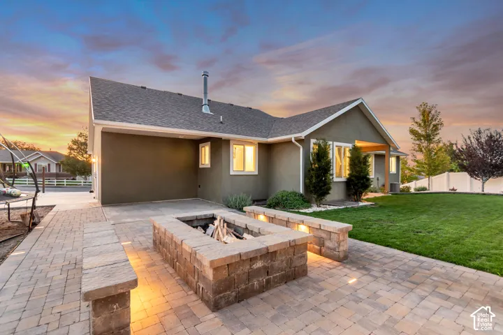 Paver patio with a stone fire pit, built-in seating, and integrated lighting