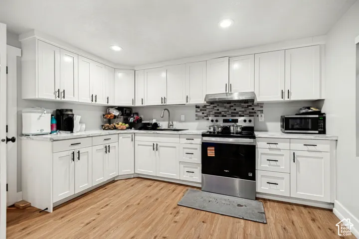 Modern kitchen featuring white shaker cabinetry, light-toned countertops, wood-finish flooring, recessed lighting, and a mosaic tile backsplash