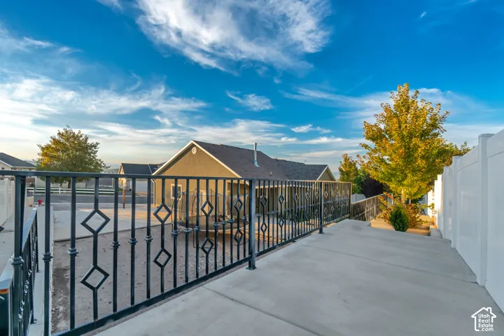 Upper terrace concrete pathway with ornamental metal railing and white privacy fencing