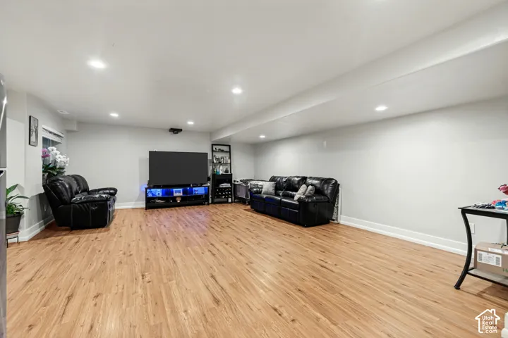 Spacious recreation room featuring wood-finish flooring, recessed lighting, and light-toned walls