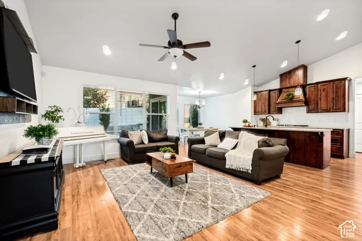 Spacious open-concept living area featuring wood-finish flooring, a ceiling fan, recessed lighting, and large windows