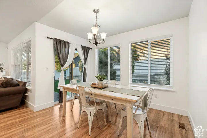 Vaulted ceiling, wood-finish flooring, white walls, multiple windows, and a sliding glass door
