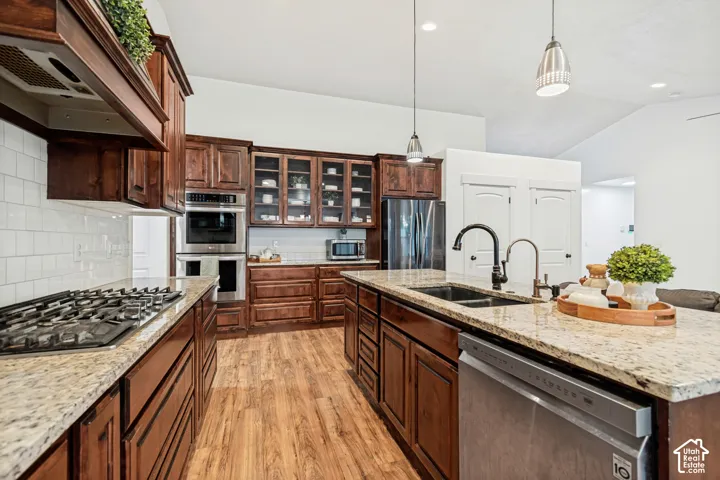 Kitchen featuring wood-finish flooring, dark wood cabinetry, light-toned countertops, a gas cooktop, and a double basin sink with a gooseneck faucet