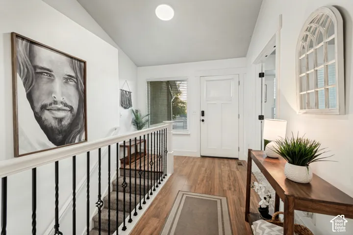Entryway featuring wood-finish flooring, a white paneled door with smart lock, and a staircase with wrought iron spindles