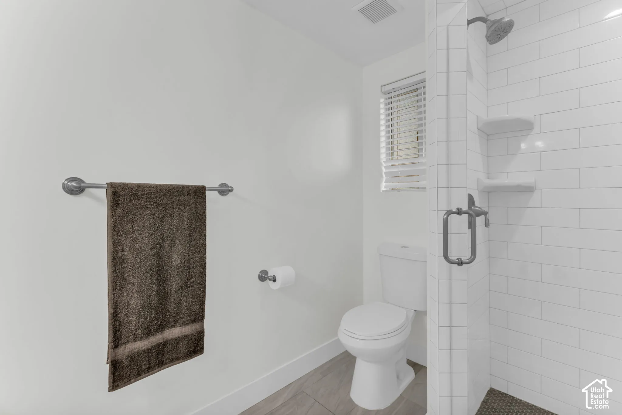 White subway tile shower enclosure with built-in shelving and glass door