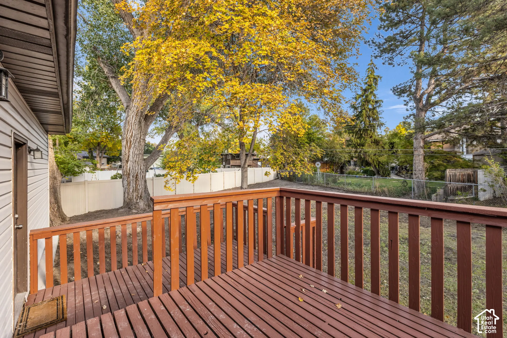 Private wooden deck with railing, siding exterior, and mature trees