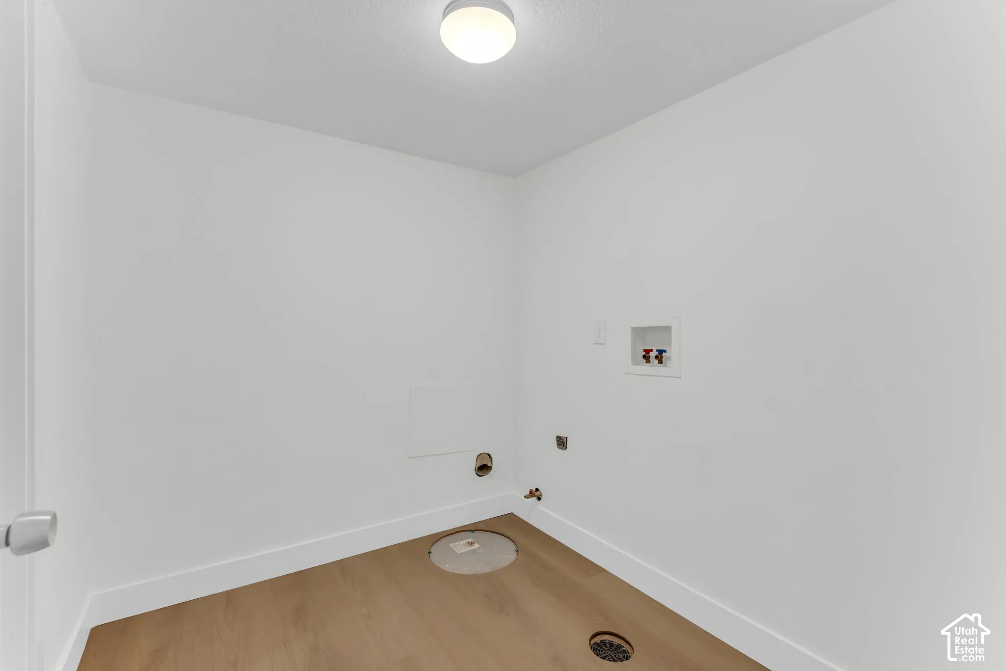 Laundry area with wood-finish flooring, white walls, and a ceiling-mounted light fixture