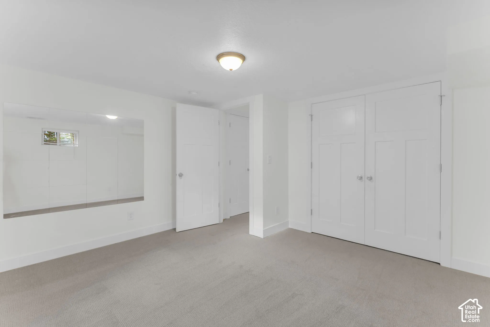 Recessed ceiling light, wall-mounted mirror, white paneled doors, and light-toned carpeting