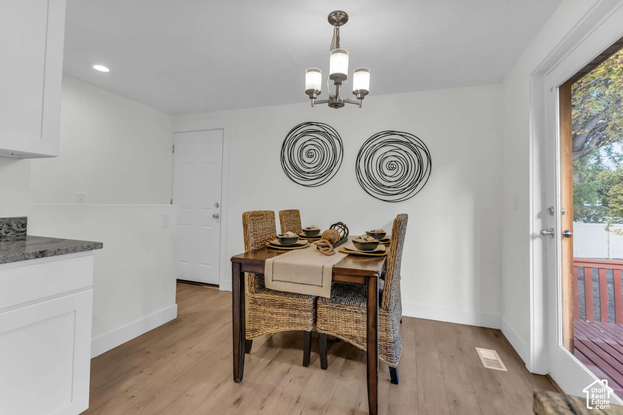 Wood-finish flooring, white cabinetry, and granite-look countertop