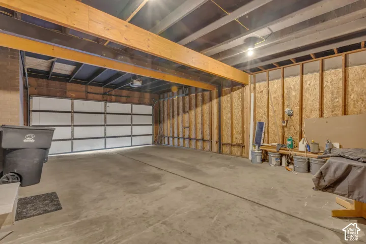 Unfinished garage space with a concrete floor, exposed wooden ceiling joists, and a sectional garage door