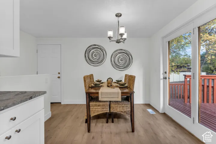 White shaker cabinetry with dark countertop, wood-finish flooring, and a multi-light chandelier