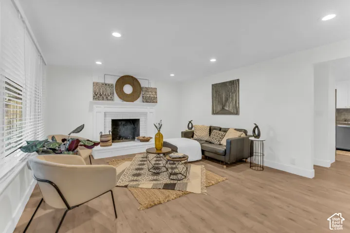 Bright living area featuring wood-finish flooring, recessed lighting, and a white fireplace with a classic mantel