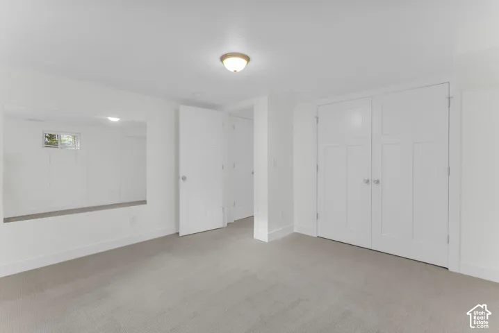 Recessed ceiling light, wall-mounted mirror, white paneled doors, and light-toned carpeting