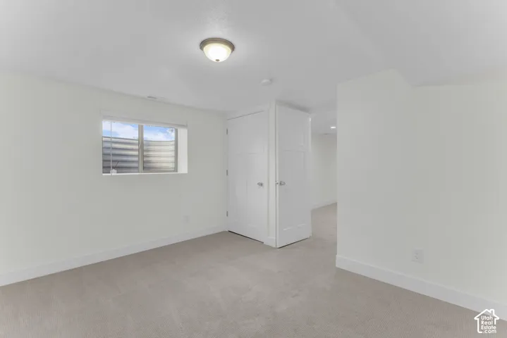Recessed window with natural light, neutral carpet, white painted walls, and ceiling-mounted light fixture