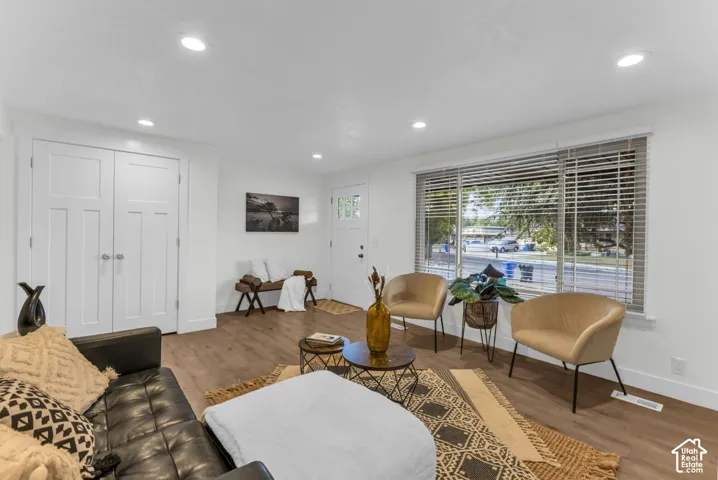 Recessed lighting, wood-finish flooring, white trim details, and a large window with horizontal blinds