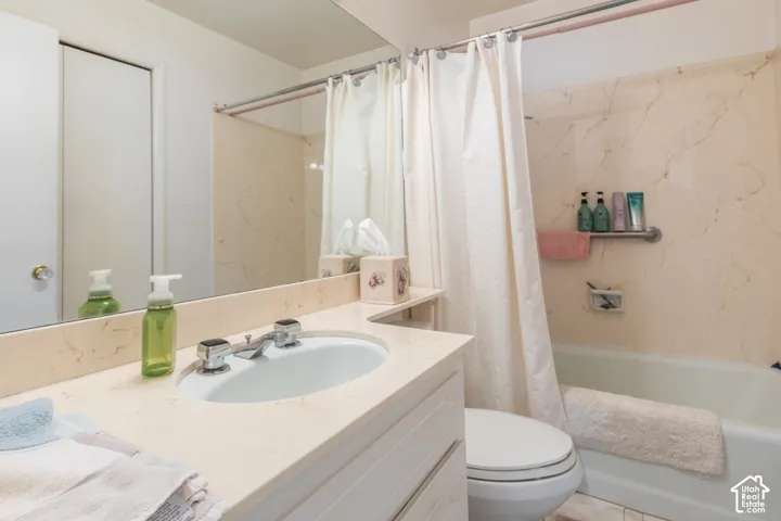 Bathroom featuring a built-in vanity with an integrated sink and chrome faucet, a large wall-mounted mirror, and a bathtub with a grab bar