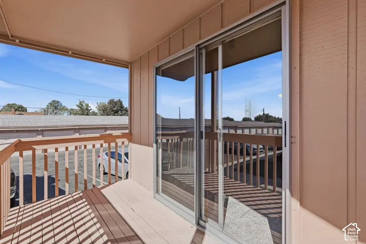 Outdoor covered balcony featuring wood decking, wood railing, and sliding glass door access