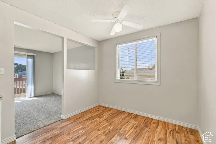 Wood-finish flooring, overhead ceiling fan with lighting, and a window with blinds