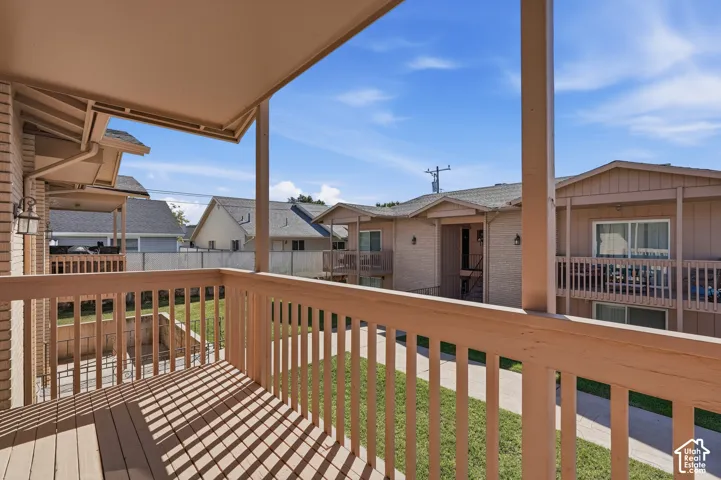 Balcony with wood decking, light brown railing, and an overhead awning