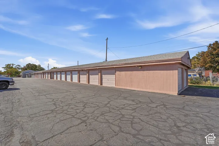 Long row of  garage units with individual roll-up doors, a light-colored shingle roof.