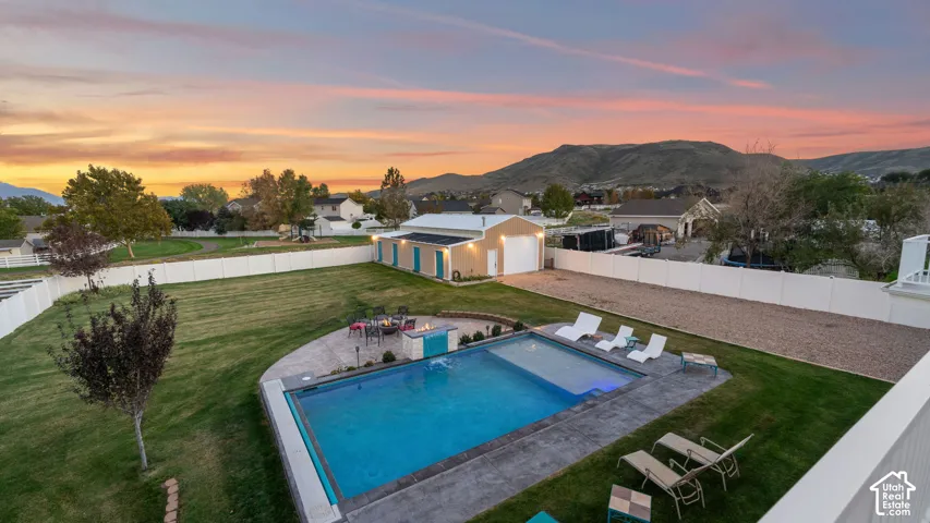 Expansive green lawn with an in-ground swimming pool, surrounded by concrete hardscaping