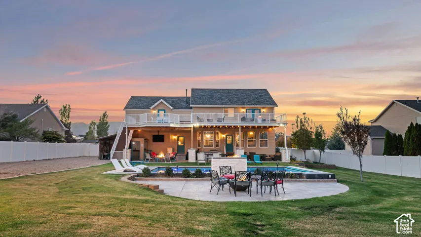 Expansive backyard featuring a built-in swimming pool, integrated hot tub, fire pit, concrete patio, and a covered outdoor living area