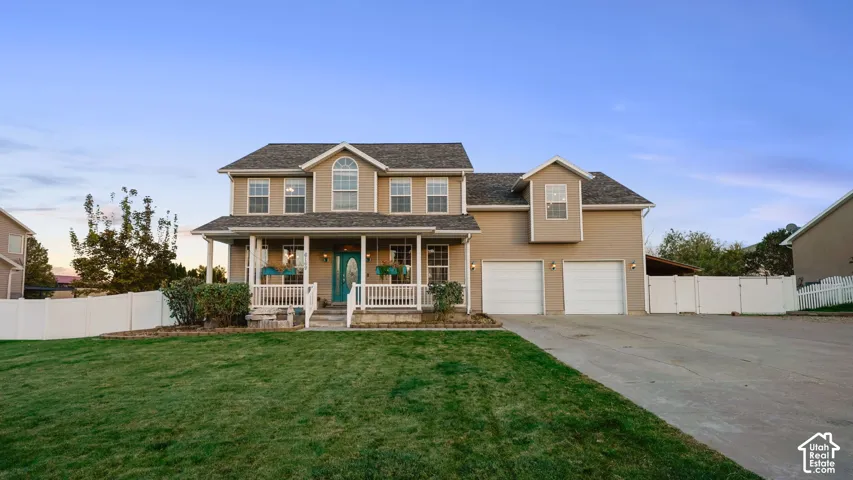 Two-story residence featuring a covered front porch, an arched transom window, a two-car garage, and a white picket fence