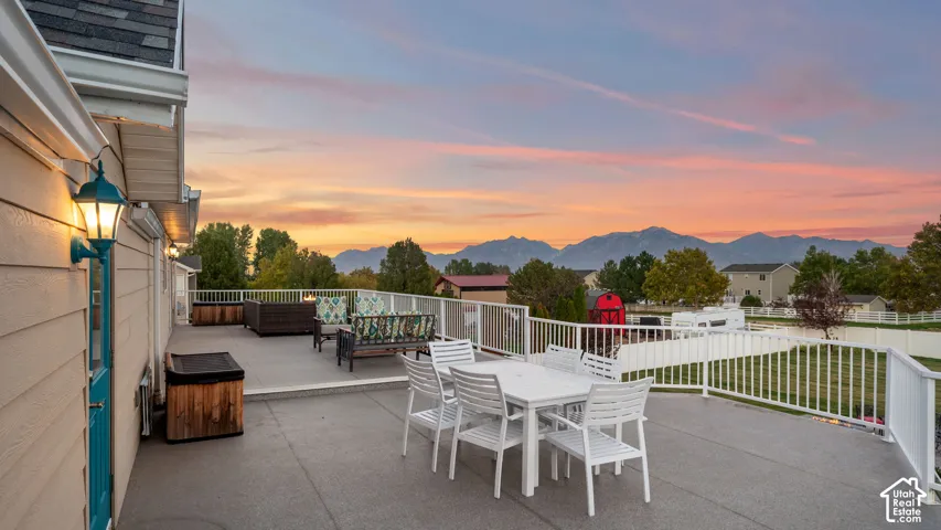 Expansive outdoor deck featuring mountain scenery, protective railing, and exterior wall lighting