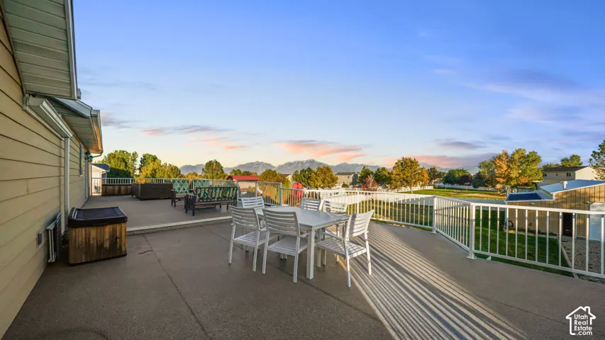 Expansive elevated concrete patio with white railing, offering distant mountain scenery
