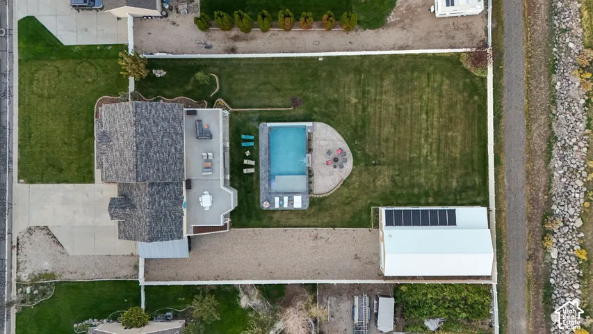 Expansive property featuring a swimming pool, detached garage with solar panels, gravel pathways, and a paved driveway