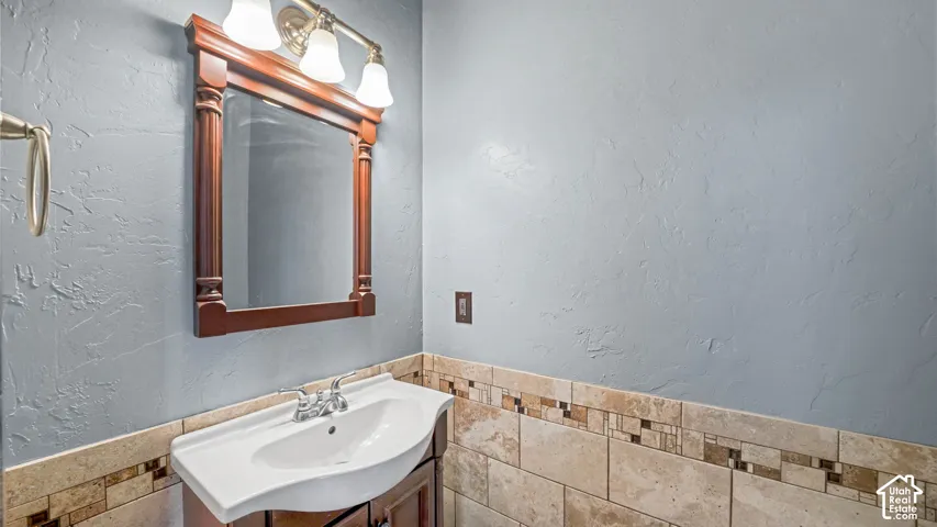 Pedestal sink with chrome fixtures, wood-finish vanity, and a decorative mirror with a three-light fixture