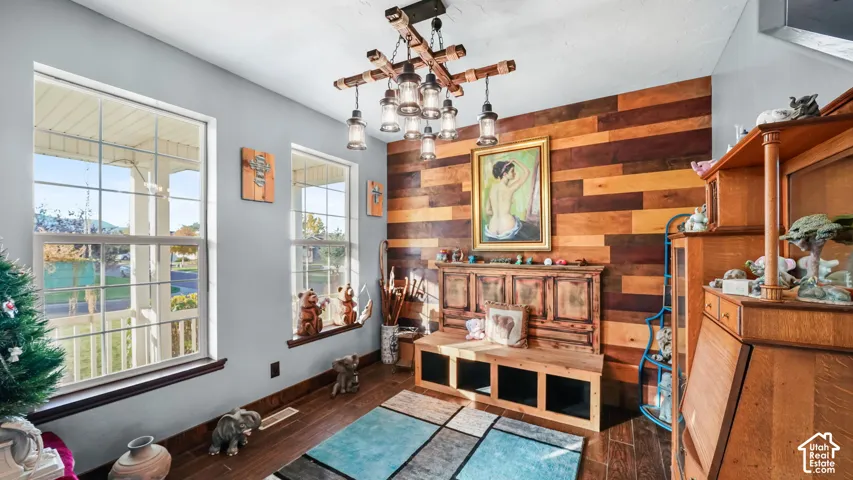 Decorative wood-plank accent wall, wood-finish flooring, and a unique multi-bulb chandelier