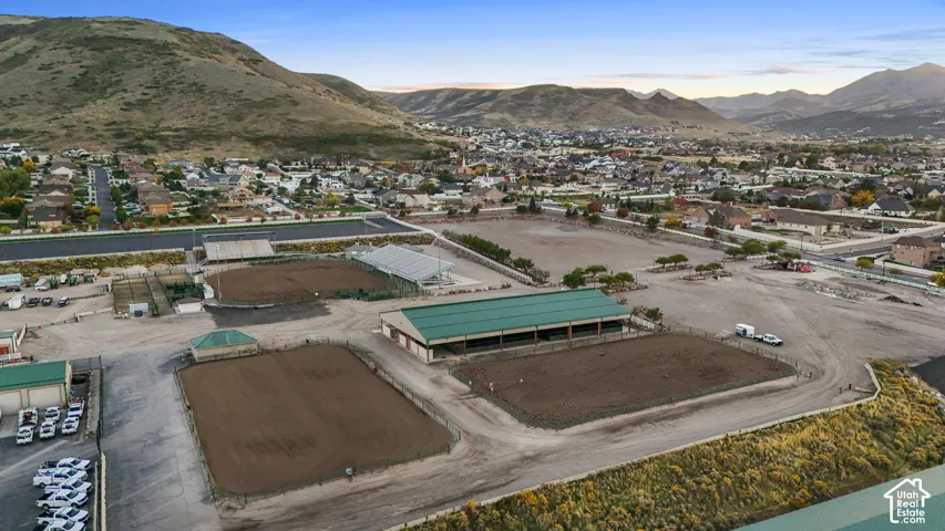 Multiple outdoor riding arenas, covered riding arena, and expansive open-air space with mountain backdrop