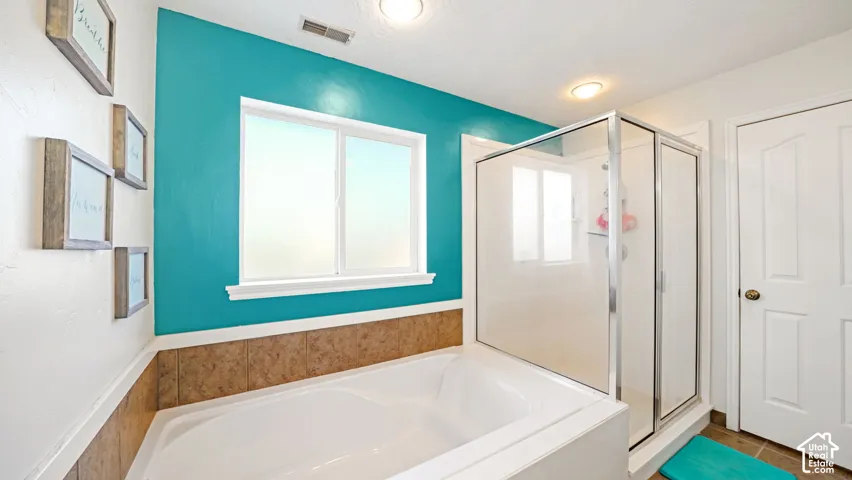Integrated soaking tub with tiled surround, separate enclosed shower, and a white framed window