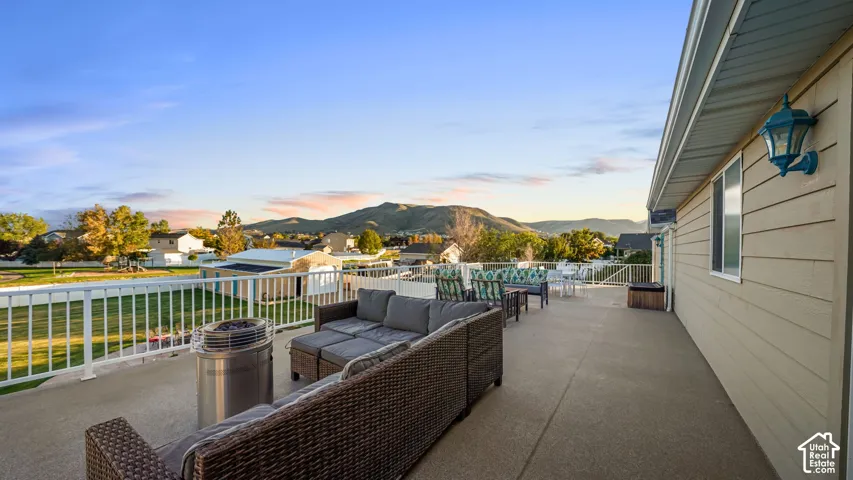 Expansive outdoor patio with durable concrete surface, white railing, and exterior wall lighting